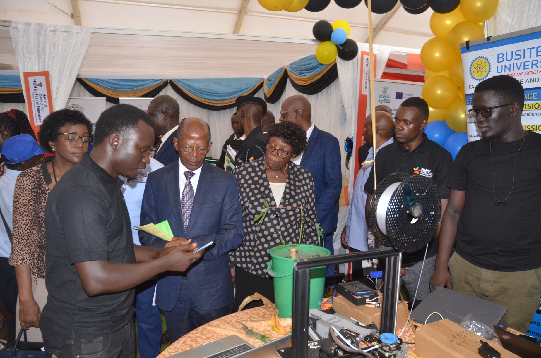 State Minister for Higher Education, Dr. J.C. Muyingo, tours the Busitema University exhibition stall, engaging with students and exploring their innovative projects