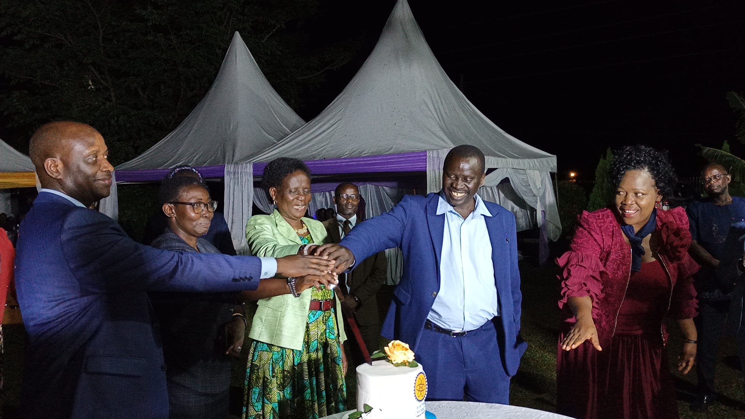 The Vice Chancellor, Prof. Paul Waako, accompanied by the Deputy Vice Chancellors, joins Mrs. Sophia Acon in cutting a cake during her farewell ceremony